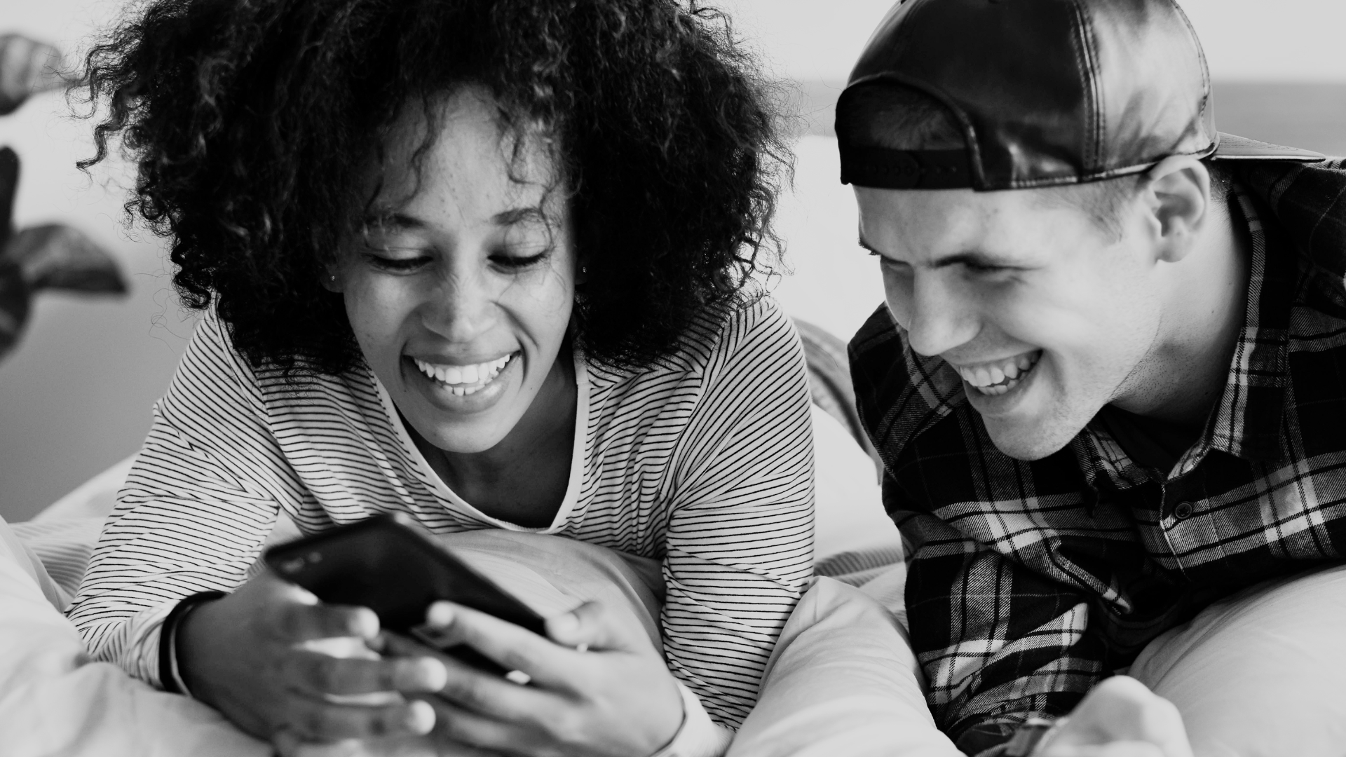 un ragazzo e una ragazza guardano un telefono sorridendo.