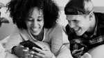 un ragazzo e una ragazza guardano un telefono sorridendo.