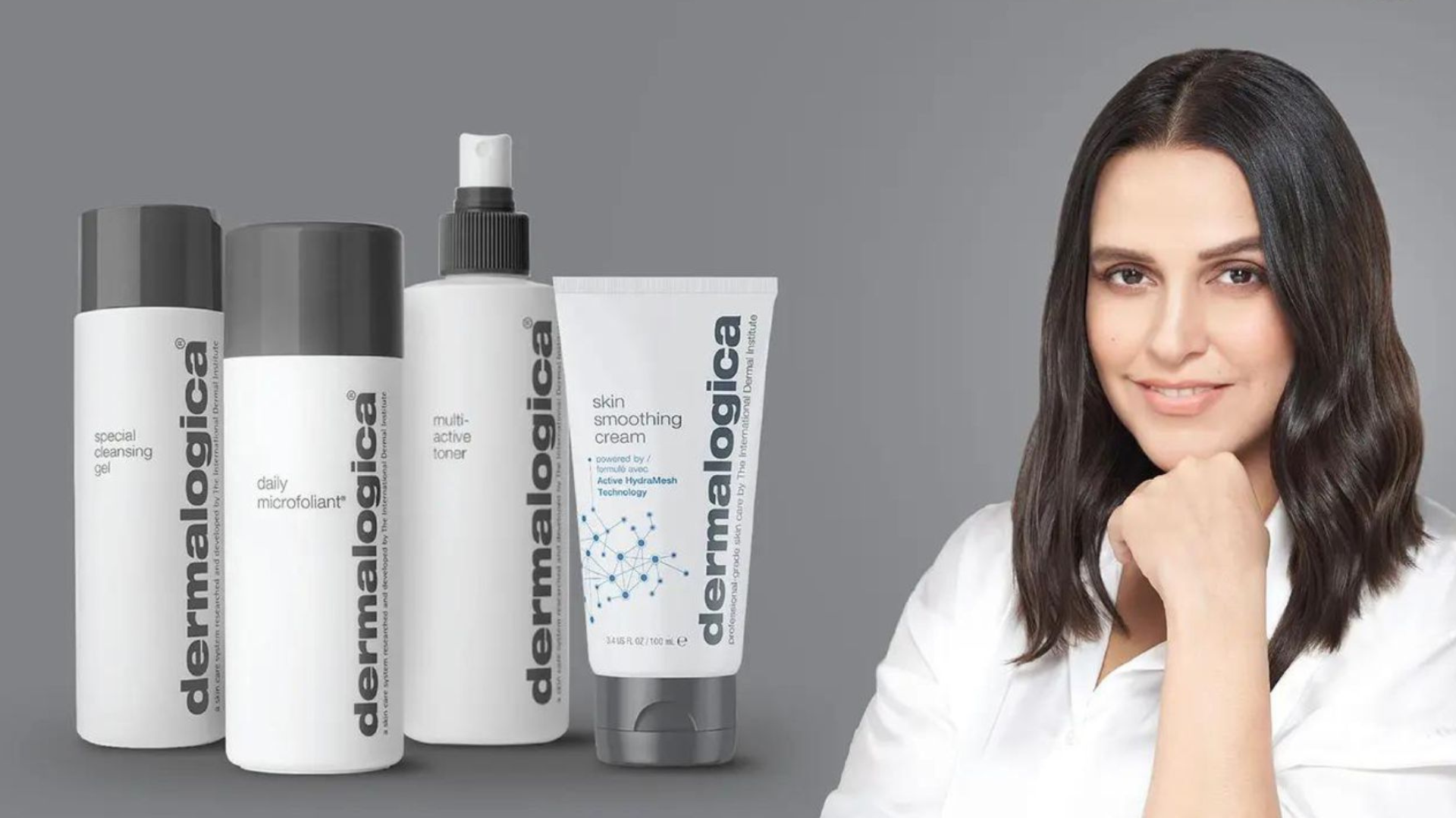 Donna sorridente con la mano sul mento accanto alle bottiglie di Dermalogica